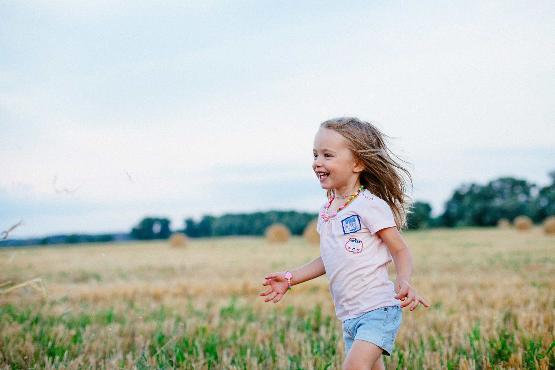 A smiling young girl running through a field