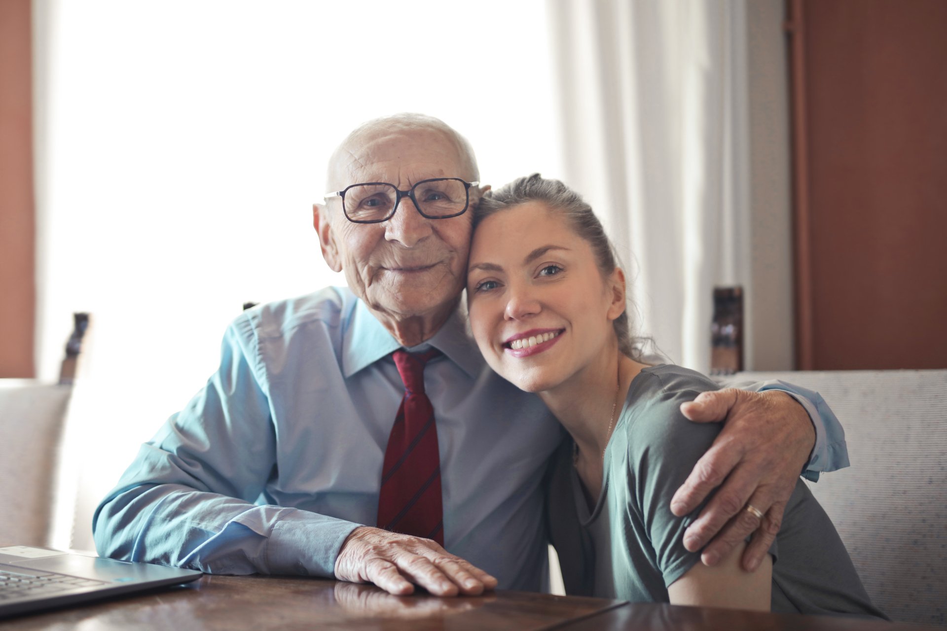 An elderly man and a younger woman sitting together at a table