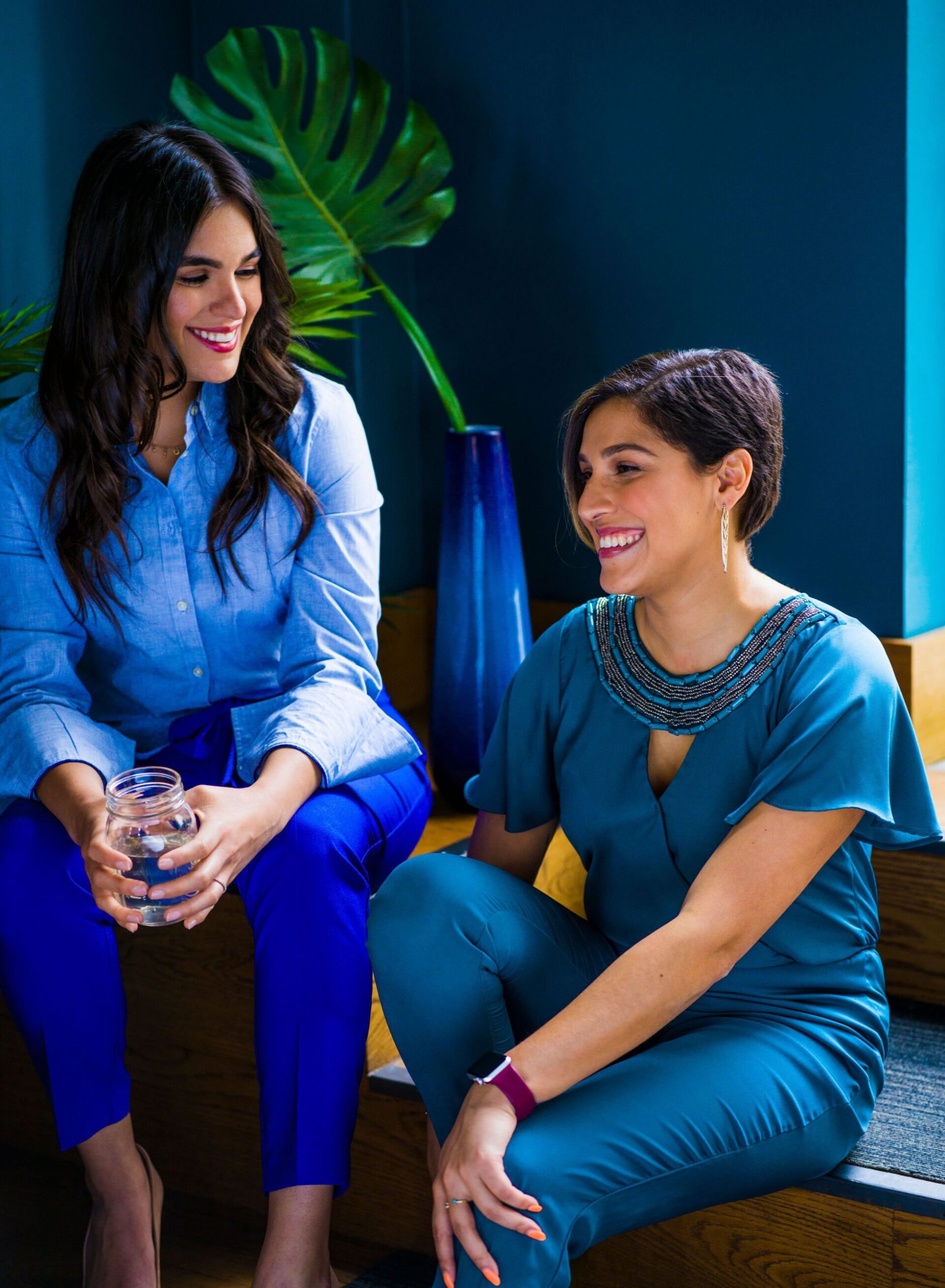 Two women in blue outfits sitting and talking